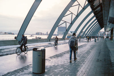 People walking on bridge in city against sky