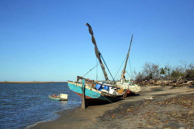 Sailboat moored on sea against clear blue sky