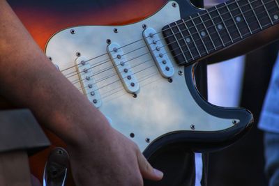 Midsection of man playing guitar