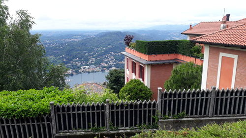 Houses by trees and buildings in city against sky