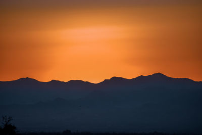 Scenic view of silhouette mountains against romantic sky at sunset