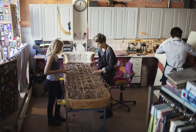 Female workers making chaise longue together at workshop