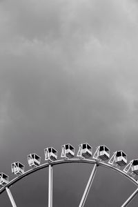 Low angle view of ferris wheel against cloudy sky