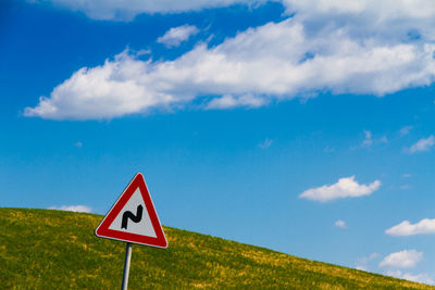 Road sign on field against sky