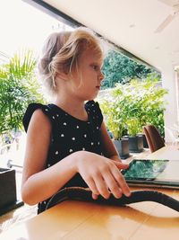 Young woman looking away while sitting on table