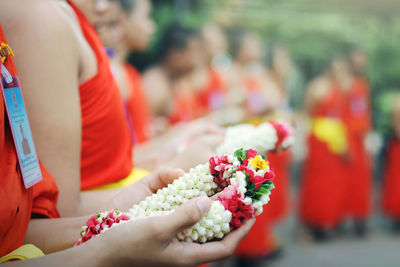 Cropped image of monks holding garland while standing outdoors