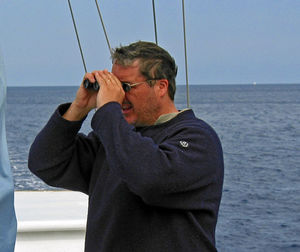 Man looking through binoculars on boat in sea
