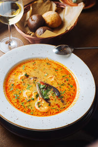 From above of appetizing aromatic tomato soup with porcini mushrooms and green herbs served on white plate