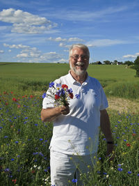 Portrait of smiling senior man holding colorful flowers