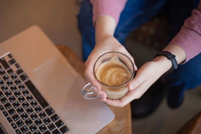 Midsection of woman holding coffee cup sitting at cafe