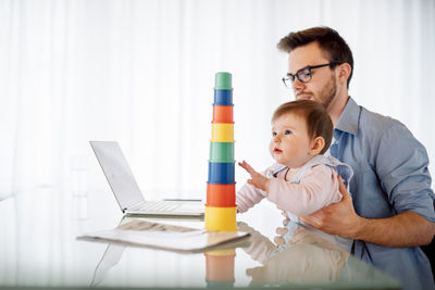 Young man with baby girl on his lap sitting at desk