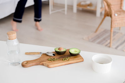 A still life sliced avocado with pumpkin seeds lies on a wooden board on a white table