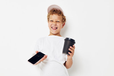 Portrait of smiling young woman using mobile phone against white background