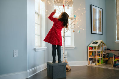 Little girl hanging christmas ornaments on modern birch christmas tree