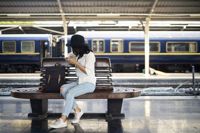 Full length of woman sitting at railroad station