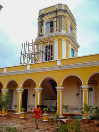 Rear view of man outside building against sky