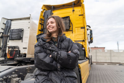 Happy mature woman standing against truck