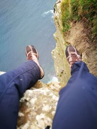 Low section of man standing on rock at shore