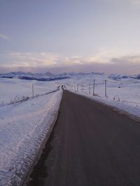 Road leading towards snowcapped mountain against sky