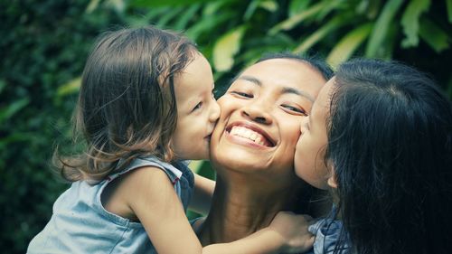 Close-up of girls kissing smiling mother