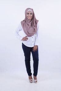 Portrait of smiling young woman standing against white background