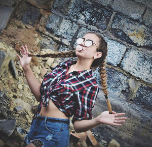 Young woman with arms raised standing against wall