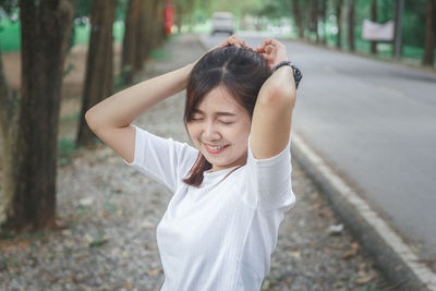 Smiling young woman with eyes closed standing in park