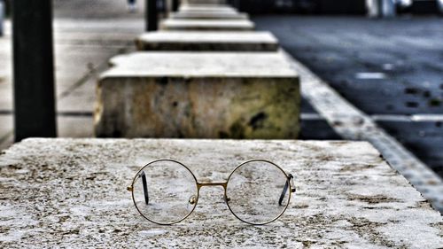 Close-up of eyeglasses on concrete seat