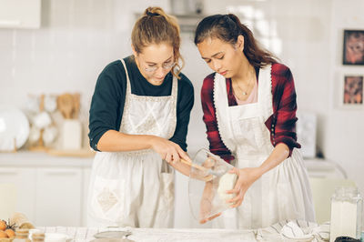 Young woman holding food while standing in kitchen