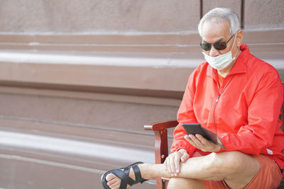 Midsection of man using mobile phone while sitting outdoors