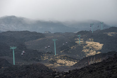 View of cable cars moving over volcanic landscape of mount etna covered in smoke