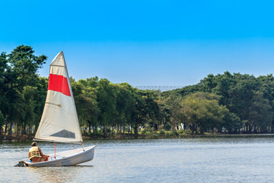 Sailboat sailing on sea against clear blue sky