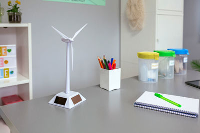 Solar windmill and selective trash bins over desk in classroom