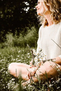 Midsection of woman holding plant on field