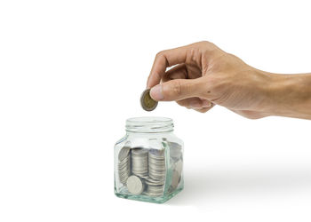 Close-up of hand holding coin against white background