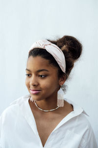 Portrait of smiling young woman standing against wall