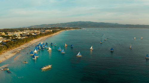 Aerial view of sailing boats on the sandy beach of boracay island at sunset time. 