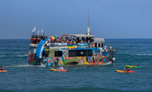 People on boats in sea against sky