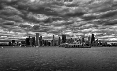 Sea by modern buildings against sky in city