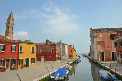 Canal passing through buildings against sky