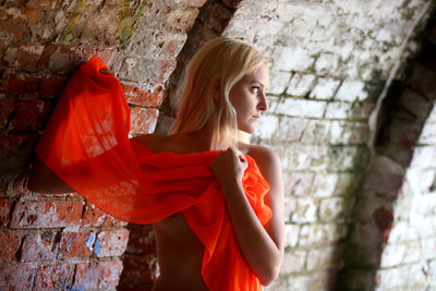 Young woman standing against wall