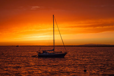 Silhouette boat sailing in sea against sky during sunset