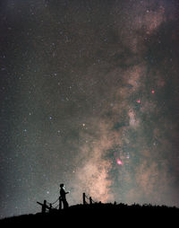 Silhouette people standing on field against sky at night