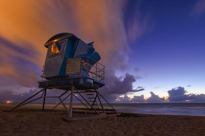 Lifeguard hut on beach against sky during sunset