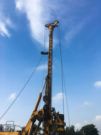 Low angle view of crane at construction site against sky