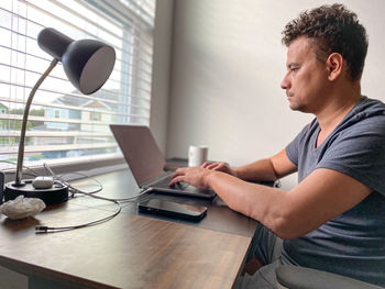 Young man working by using laptop at table