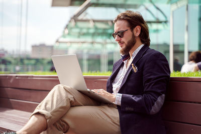 Young man using laptop while sitting on chair