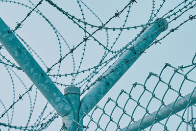 Low angle view of barbed wire fence against sky