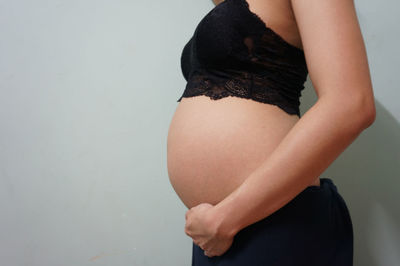 Midsection of woman touching wall against white background