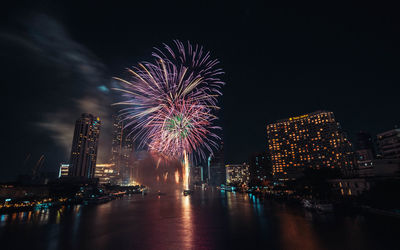 Firework display over illuminated buildings in city at night